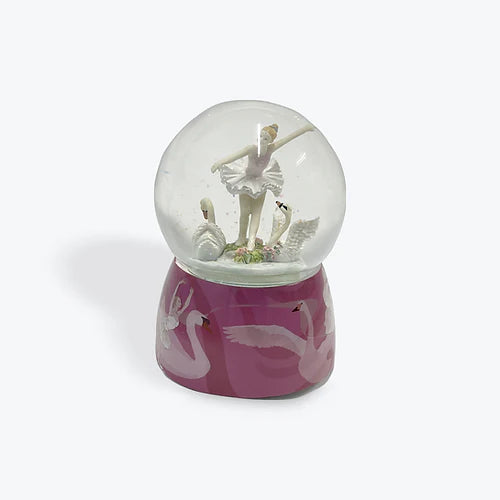 Glass snow globe with a figurine of a dancer on a pink base with flamingo designs.